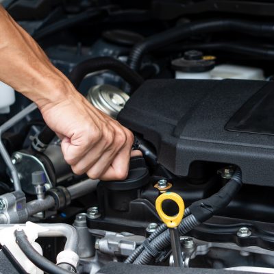Hand of car machanic checking oil and oil change in car engine and car maintenance in garage.