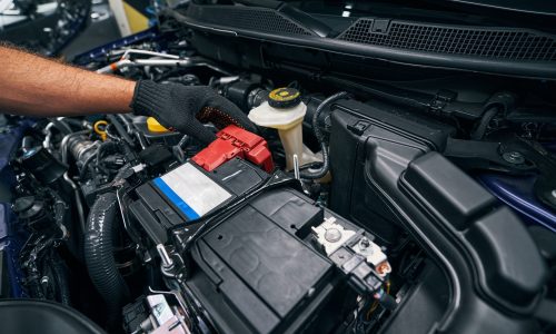 Person checking the car battery under bonnet