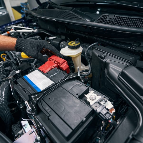 Person checking the car battery under bonnet